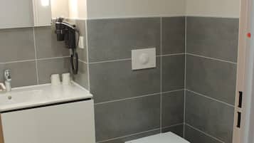Een badkamer met een wit wastafelmeubel, toilet en spiegel.