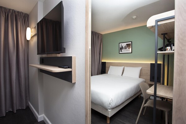 A modern hotel room with a bed, a desk, a flat-screen TV, and a wall-mounted shelf. - Kyriad Anglet-Biarritz (Anglet)