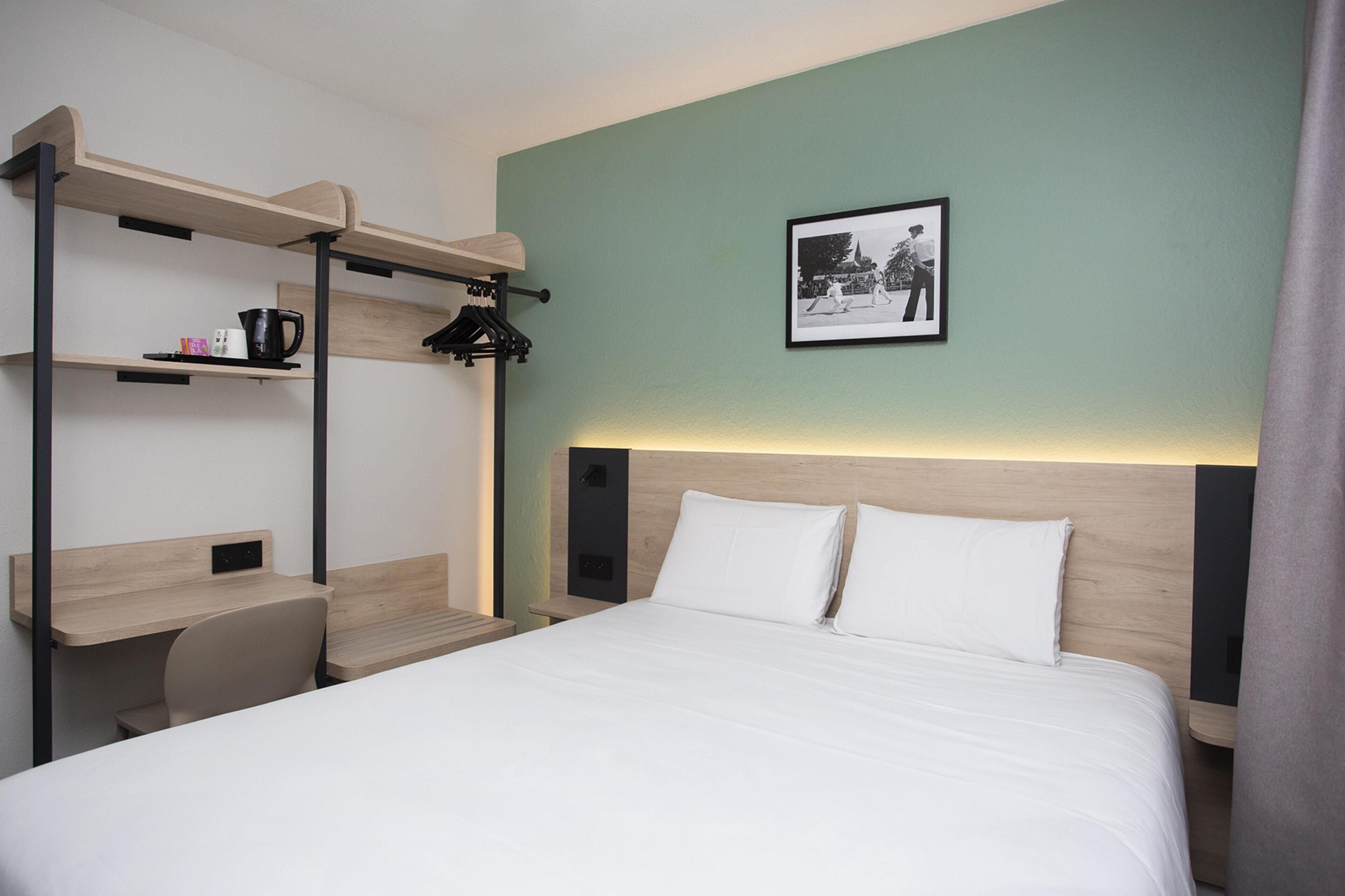 A hotel room with a bed, a desk, and a bunk bed.