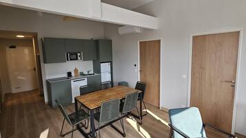 Uma cozinha compacta com uma mesa e cadeiras de madeira, micro-ondas e lava-louça.