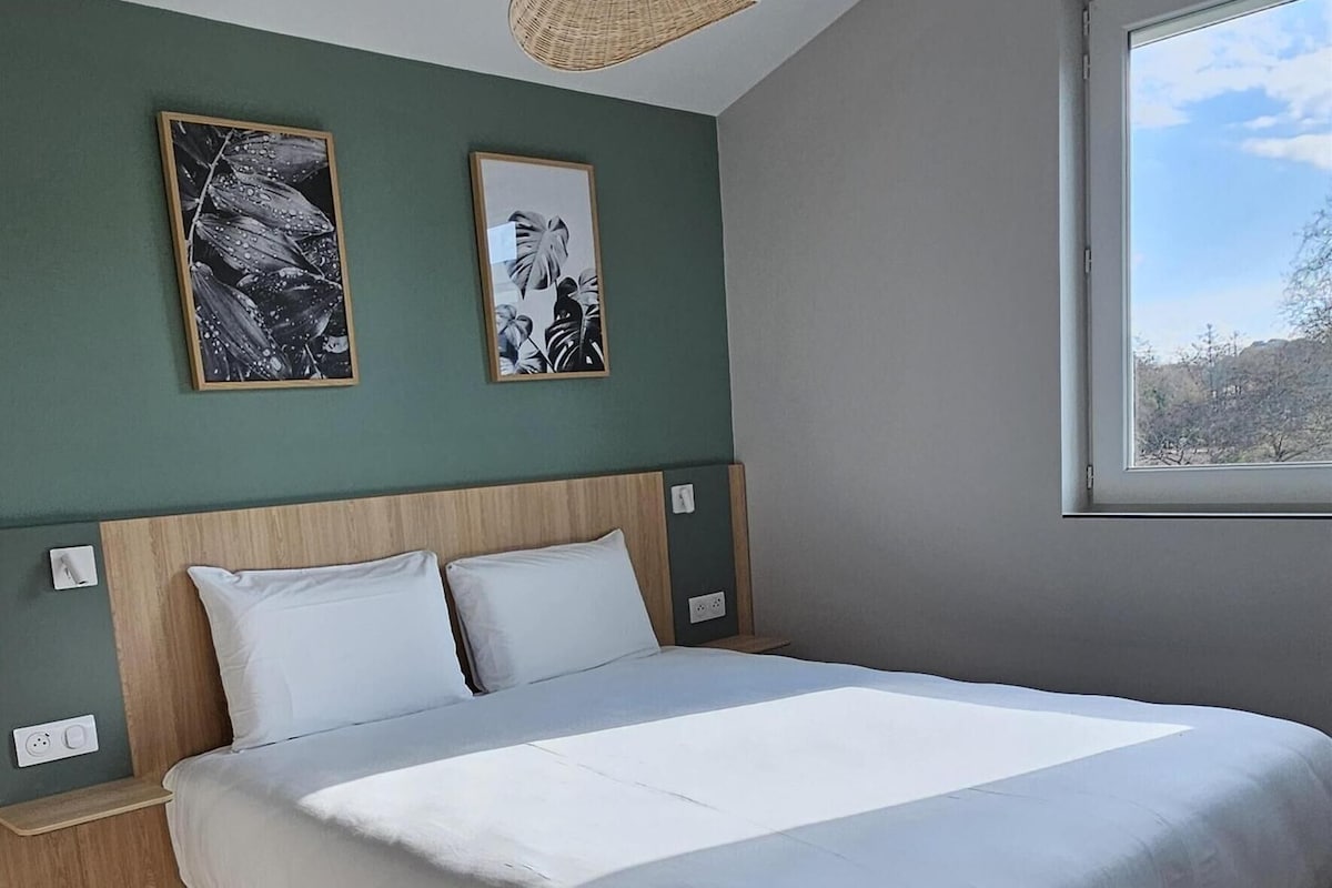 Un dormitorio con una cama grande, una lámpara colgante y dos cuadros en la pared.