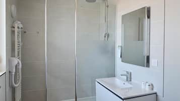 Une salle de bain moderne dotée d’une douche à parois de verre, d’un lavabo intégré, d’un miroir et d’un lave-linge.