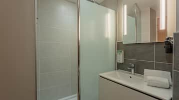 Une salle de bain moderne avec une douche à parois de verre, un lavabo avec un miroir et un porte-serviettes.