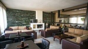 A spacious living area with multiple seating options, a fireplace, and a television. - Hotel Plaza (Alexandroupoli)