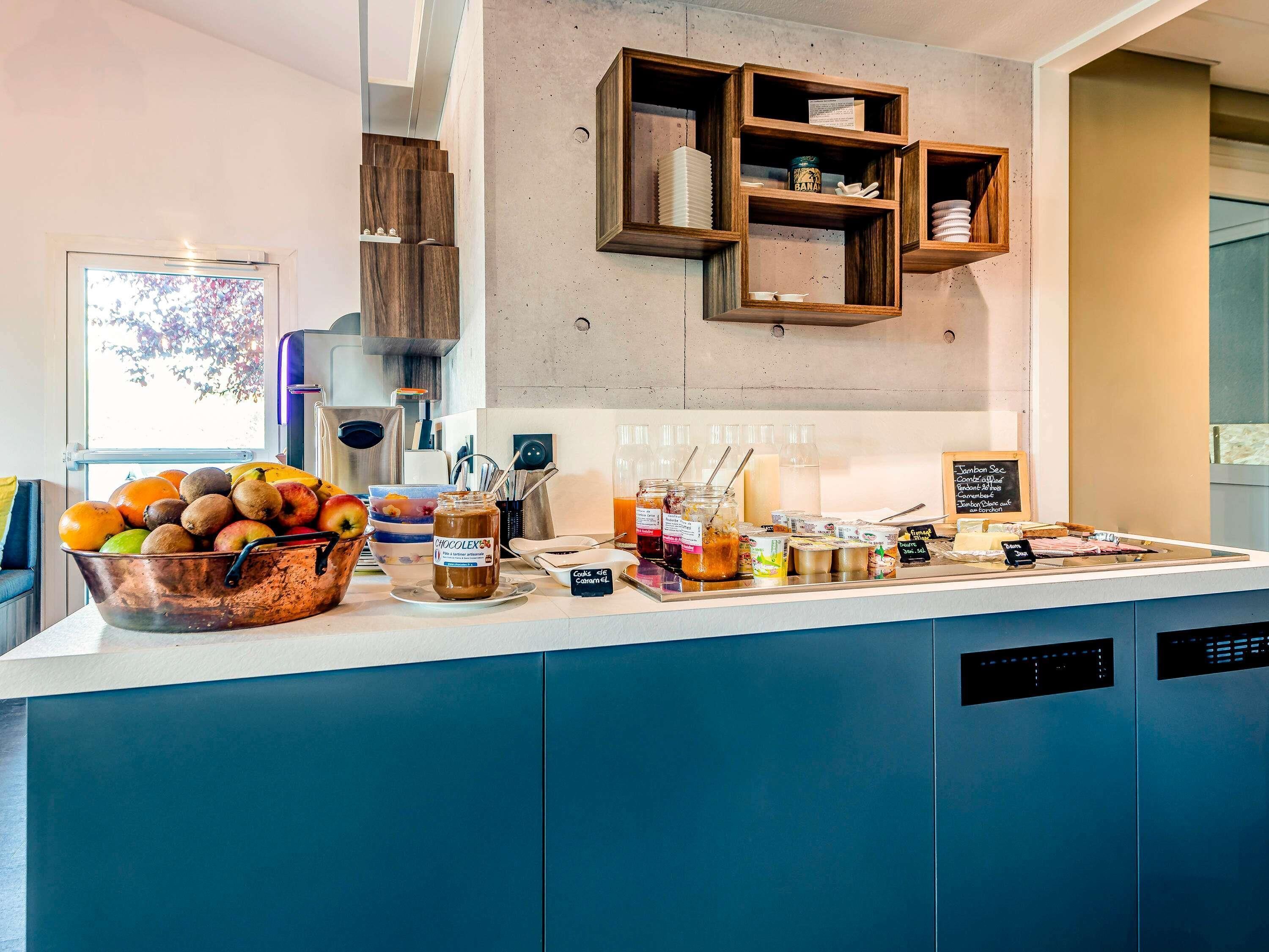 A breakfast bar with a variety of food items, a coffee machine, and a bowl of fruit.