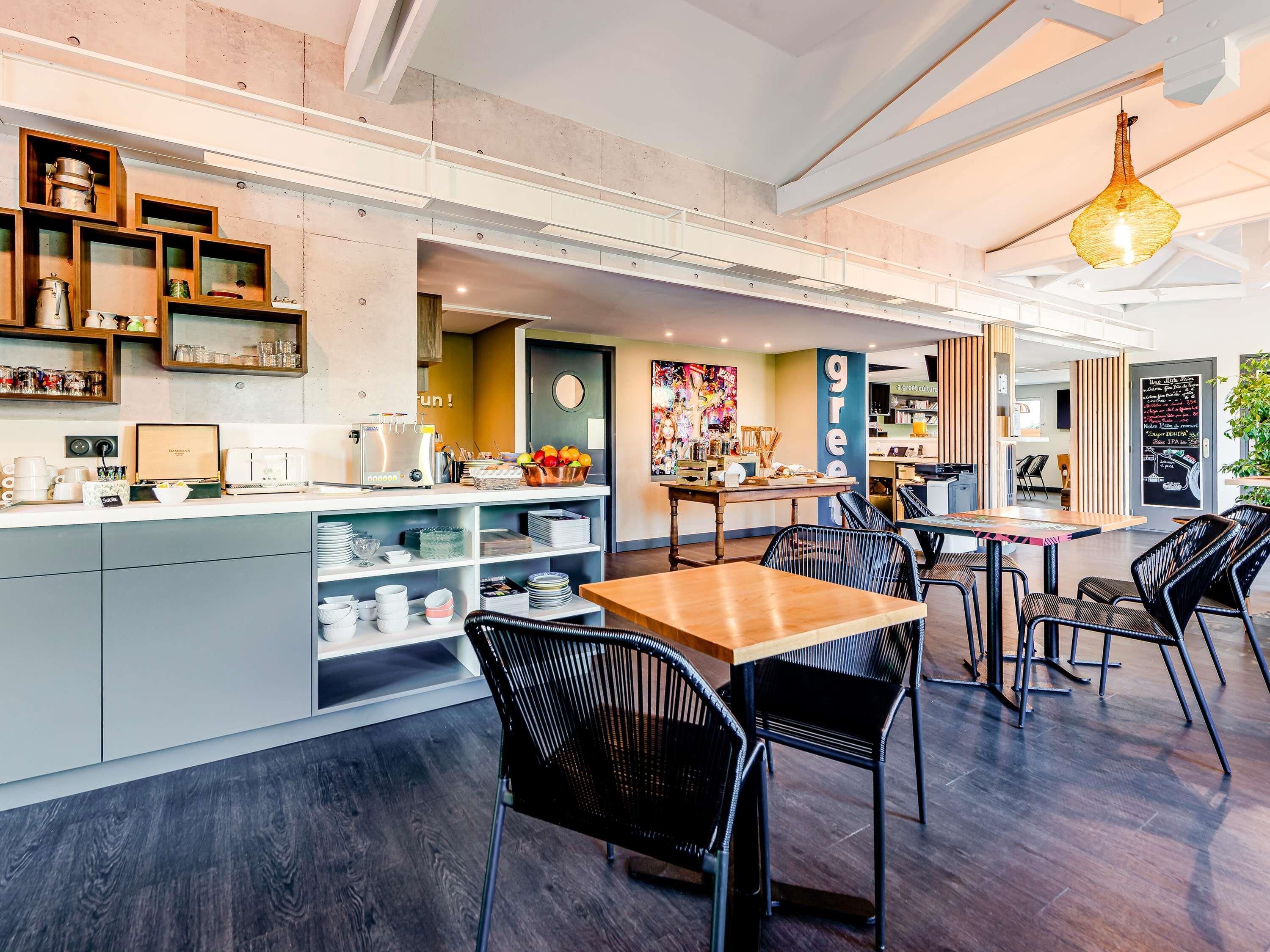 Un interno di un caffè moderno con un'isola centrale, una zona salotto e un bancone.
