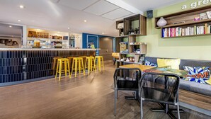 Un espace bar moderne avec des tabourets, un comptoir et un coin salon comprenant un canapé et des fauteuils.