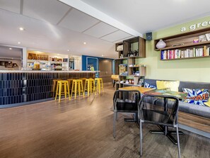 Eine moderne Bar mit Hockern, einer Theke und einer Sitzecke mit Sofa und Sesseln.