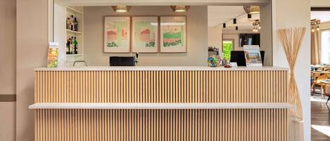 A reception desk with a wooden slat design, a white counter, and framed artwork on the wall.