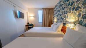 Una habitación de hotel con una cama grande, un escritorio, un televisor y una ventana con cortinas.