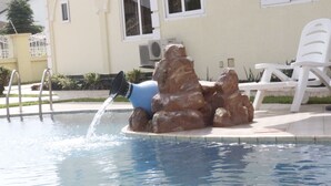 Una piscina amb una roca i una cadira blanca.