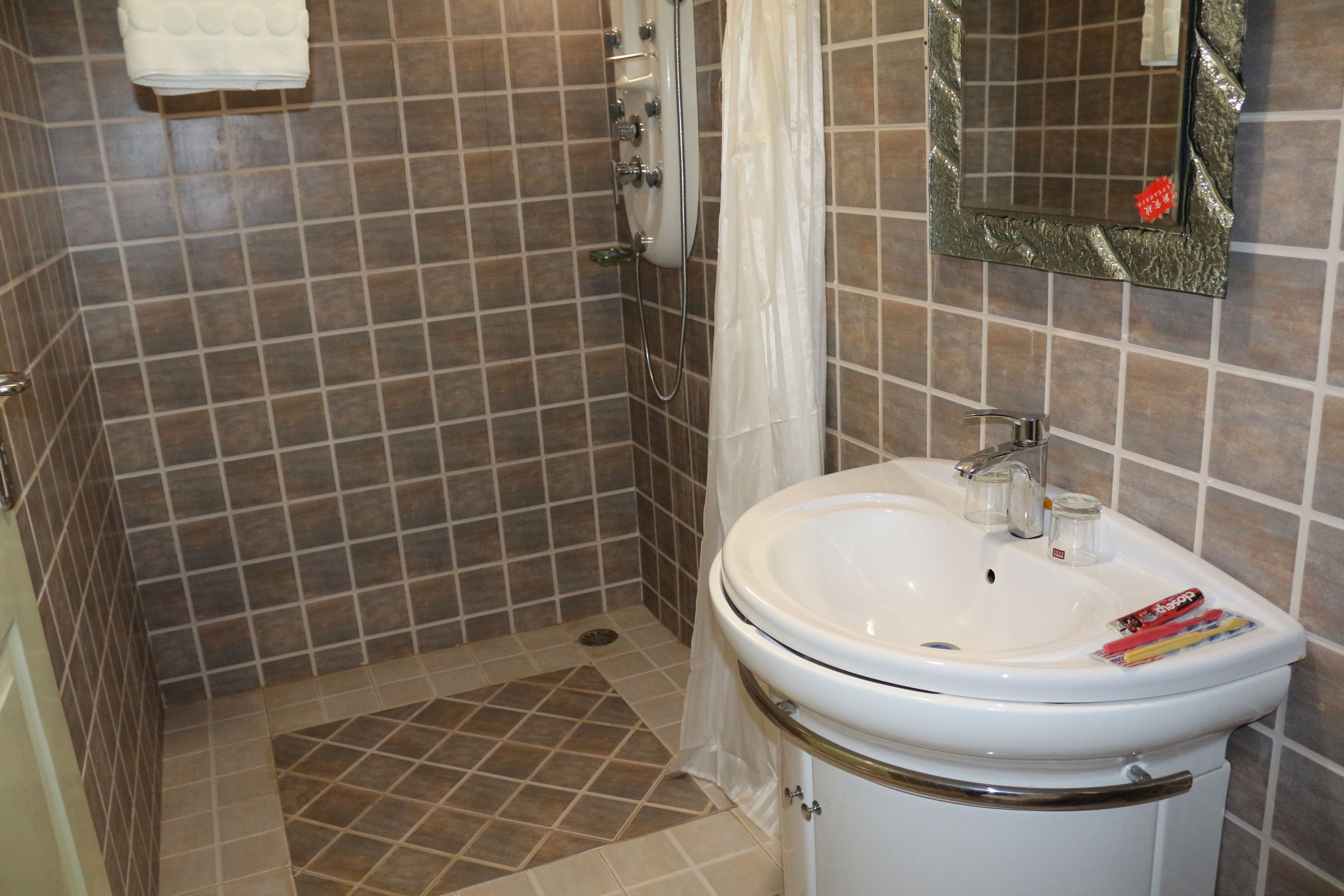 Ein Badezimmer mit einem weißen Waschbecken, einem Spiegel und einer Duschkabine.
