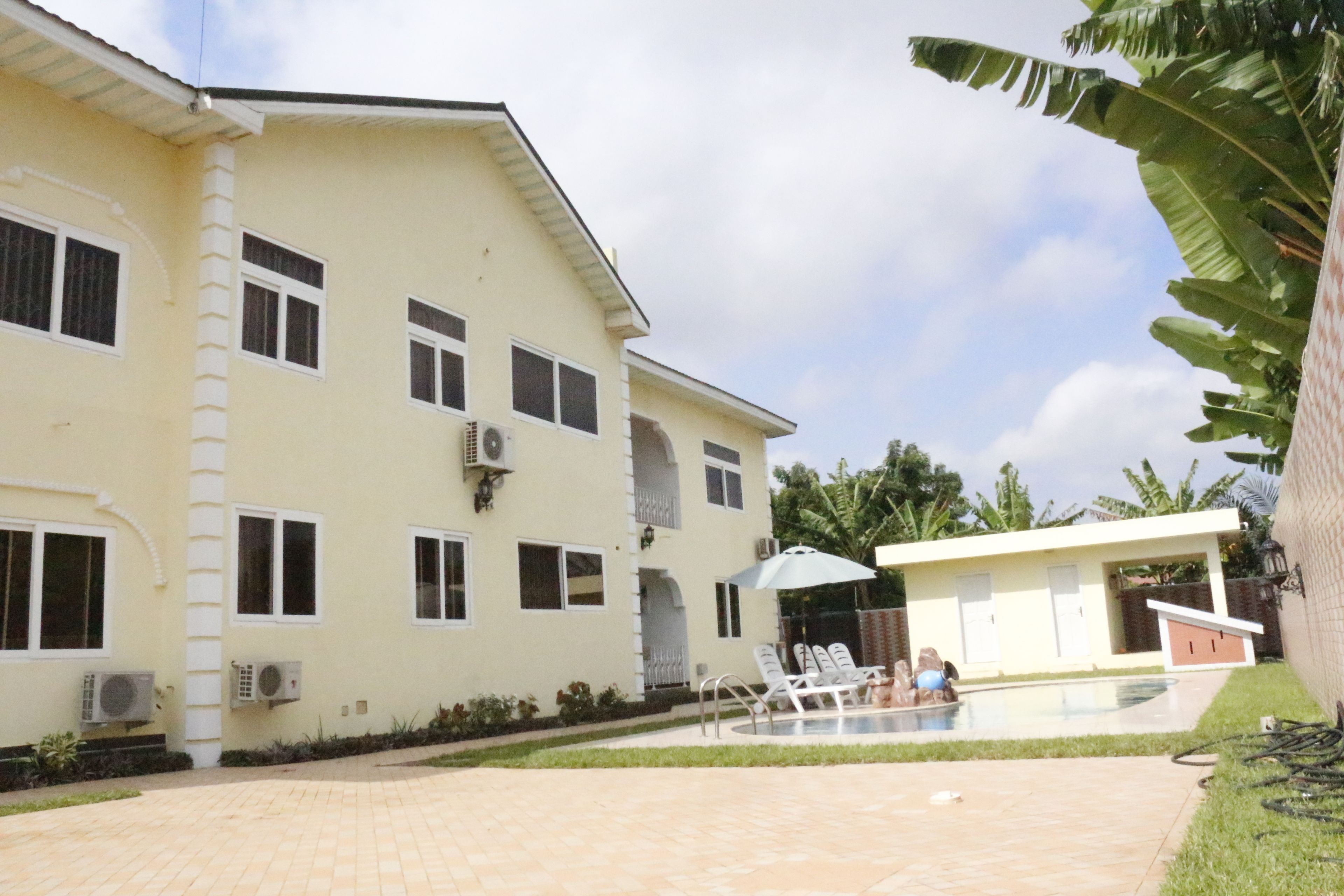 Un edificio de dos pisos con piscina, unidades de aire acondicionado y un patio cubierto.