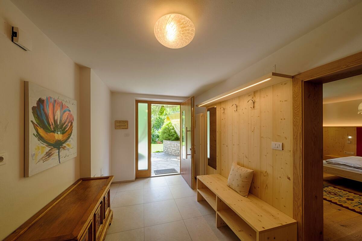 A hallway with a wooden bench, a door leading outside, and a wall-mounted artwork.