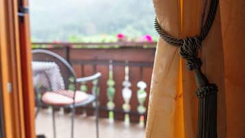 An open door leading to a balcony with a chair and a decorative rope tied to the door frame.