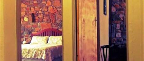 Un dormitorio con pared de piedra, puerta de madera y cama con cabecero rojo.