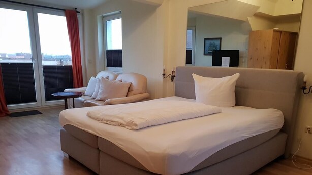 Un dormitorio moderno con una cama grande, un sofá y una mesita.