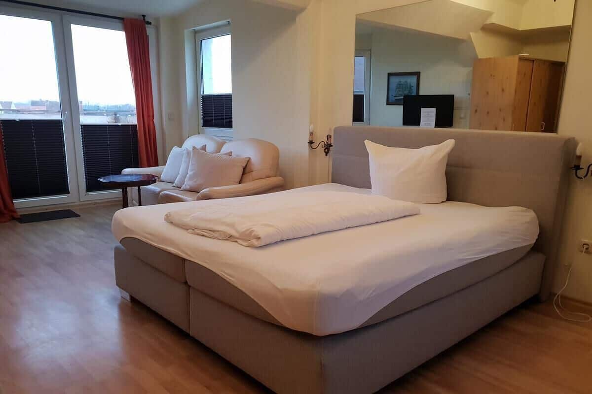 Ein modernes Schlafzimmer mit einem großen Bett, einer Couch und einem kleinen Tisch.