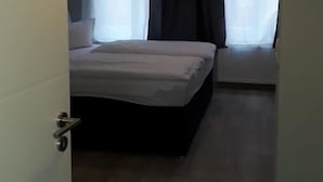 Un dormitorio con una cama, una ventana con cortinas y una lámpara colgante.