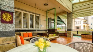 A patio area with a round table, a sofa with orange cushions, and a glass vase with yellow flowers. - Easylife B&B  (Dongshan)