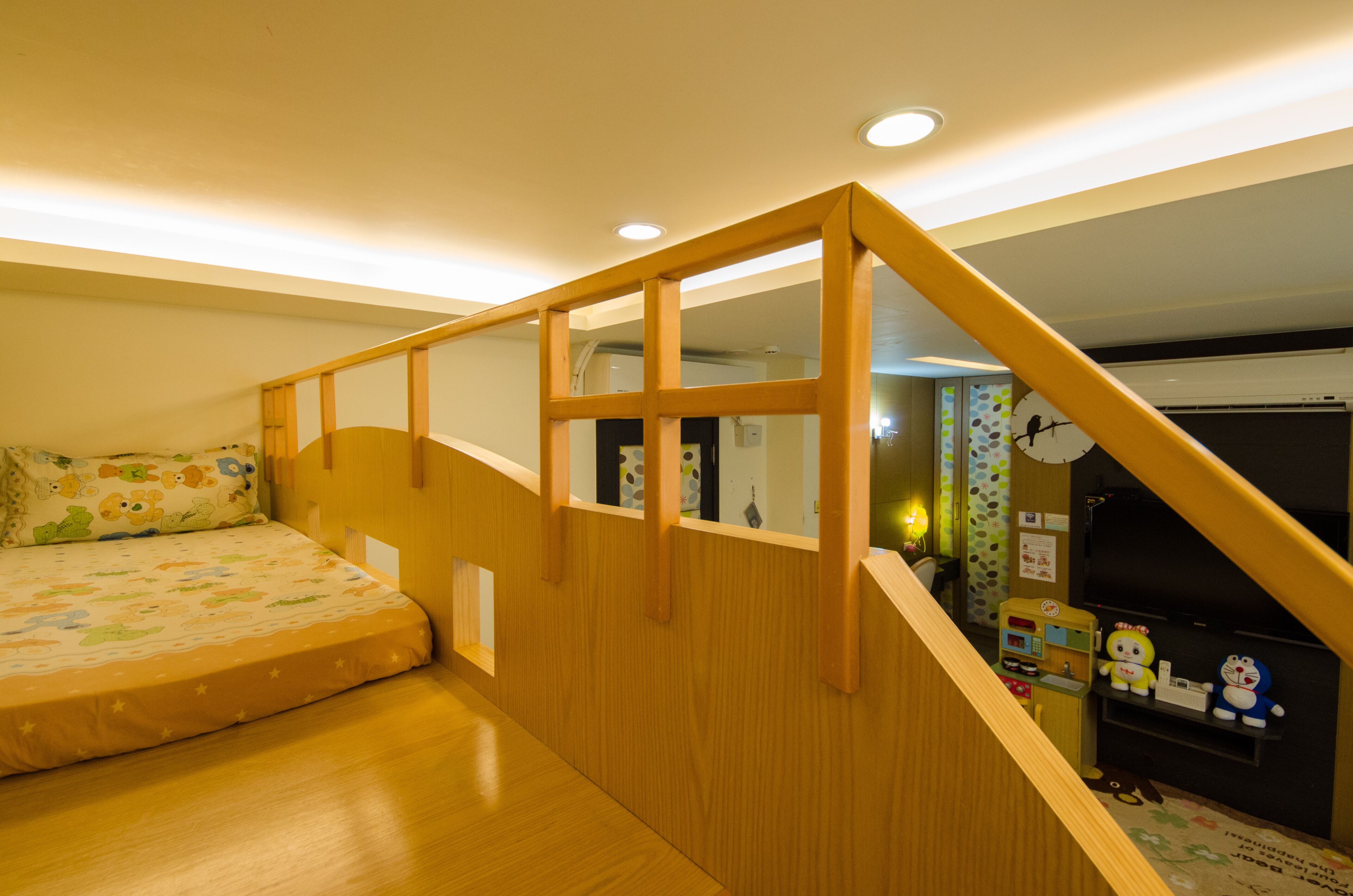 Un dormitorio con una escalera de madera, una cama con una colcha con temática de dibujos animados y una estantería con juguetes.