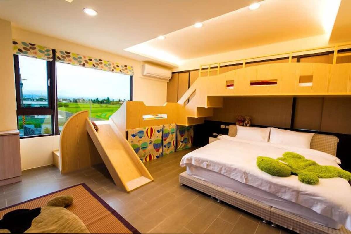 A bedroom with a bed, a slide, and a view of a green landscape.