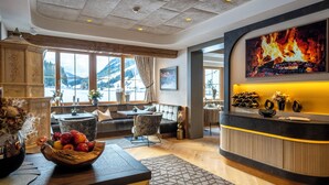 A cozy hotel lobby with a fireplace, seating area, and a fruit bowl on a wooden table. - Hotel Montanara (Ischgl)