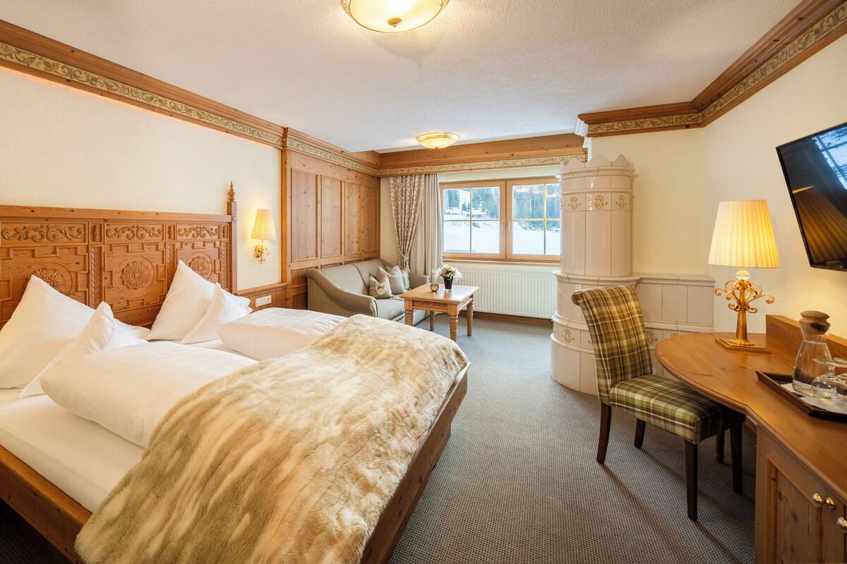 Una habitación de hotel con una cama grande, un escritorio, una silla y un televisor.