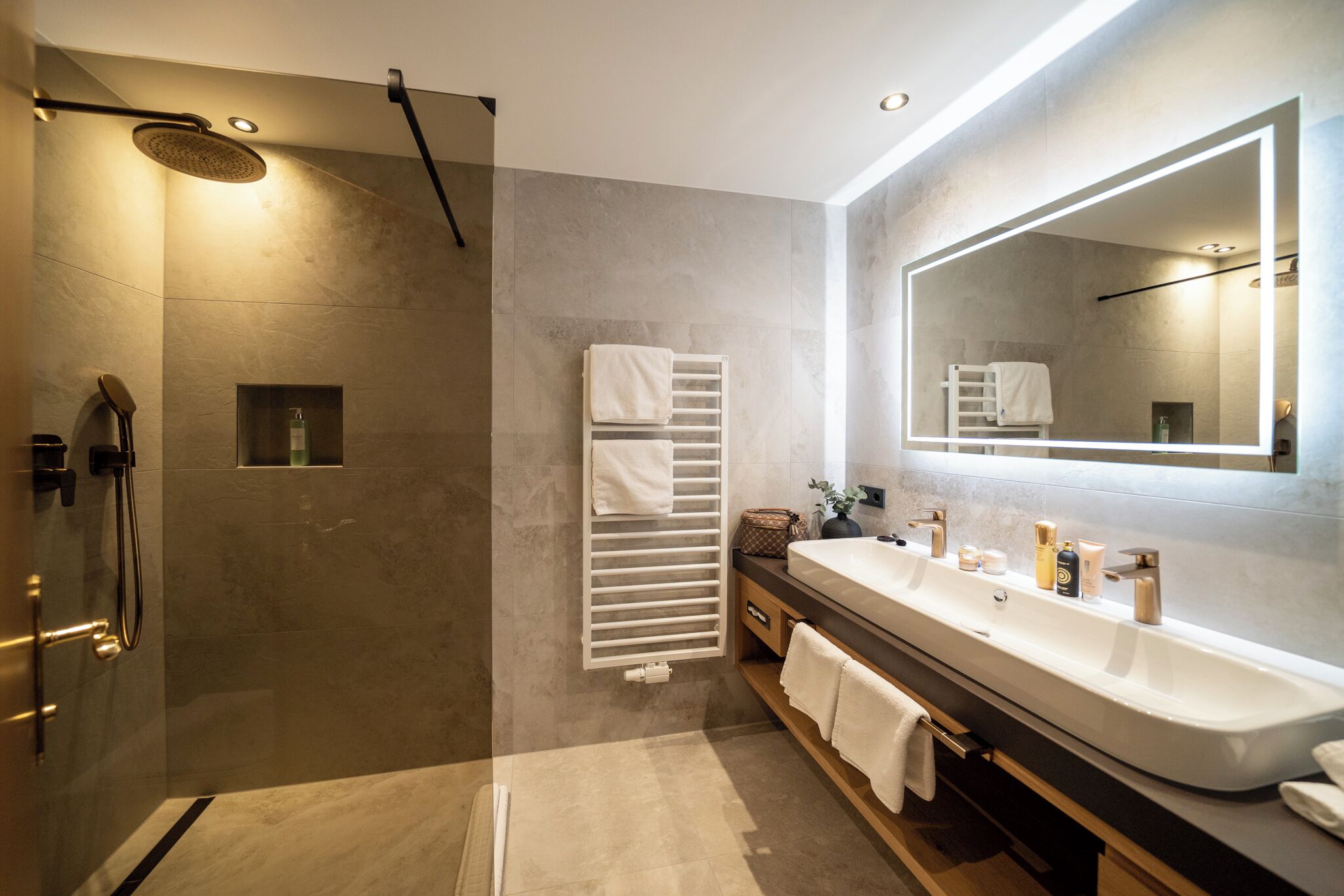 A modern bathroom with a large mirror, a walk-in shower, and a vanity with a sink and towel rack.