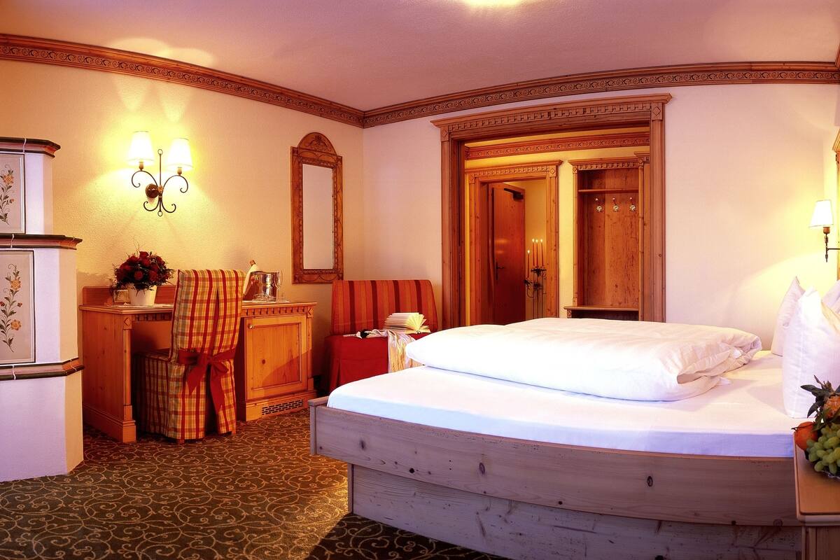 Una habitación de hotel con cama, escritorio, silla, armario y espejo.