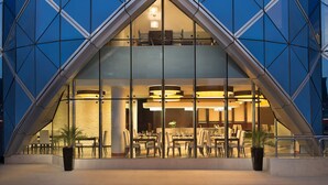 Un hotel moderno con fachada de vidrio y un área de comedor visible en su interior.