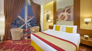 Habitación de hotel con una cama grande, un escritorio, una silla y vistas a la ciudad.