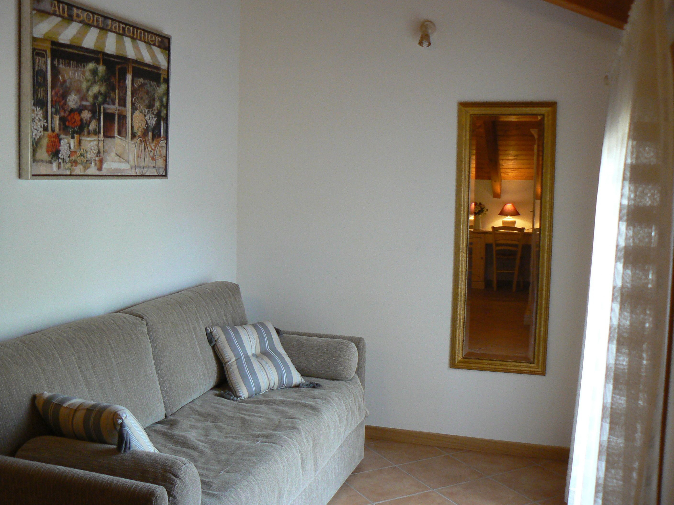 Una sala de estar con un sofá, un cuadro enmarcado en la pared y una ventana.