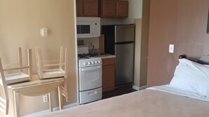 A compact RV kitchen with a stove, microwave, and refrigerator. - Rip Van Winkle Motel (Plattsburgh)