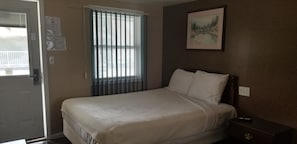 A bedroom with a bed, a window with blinds, a painting on the wall, and a door. - Rip Van Winkle Motel (Plattsburgh)