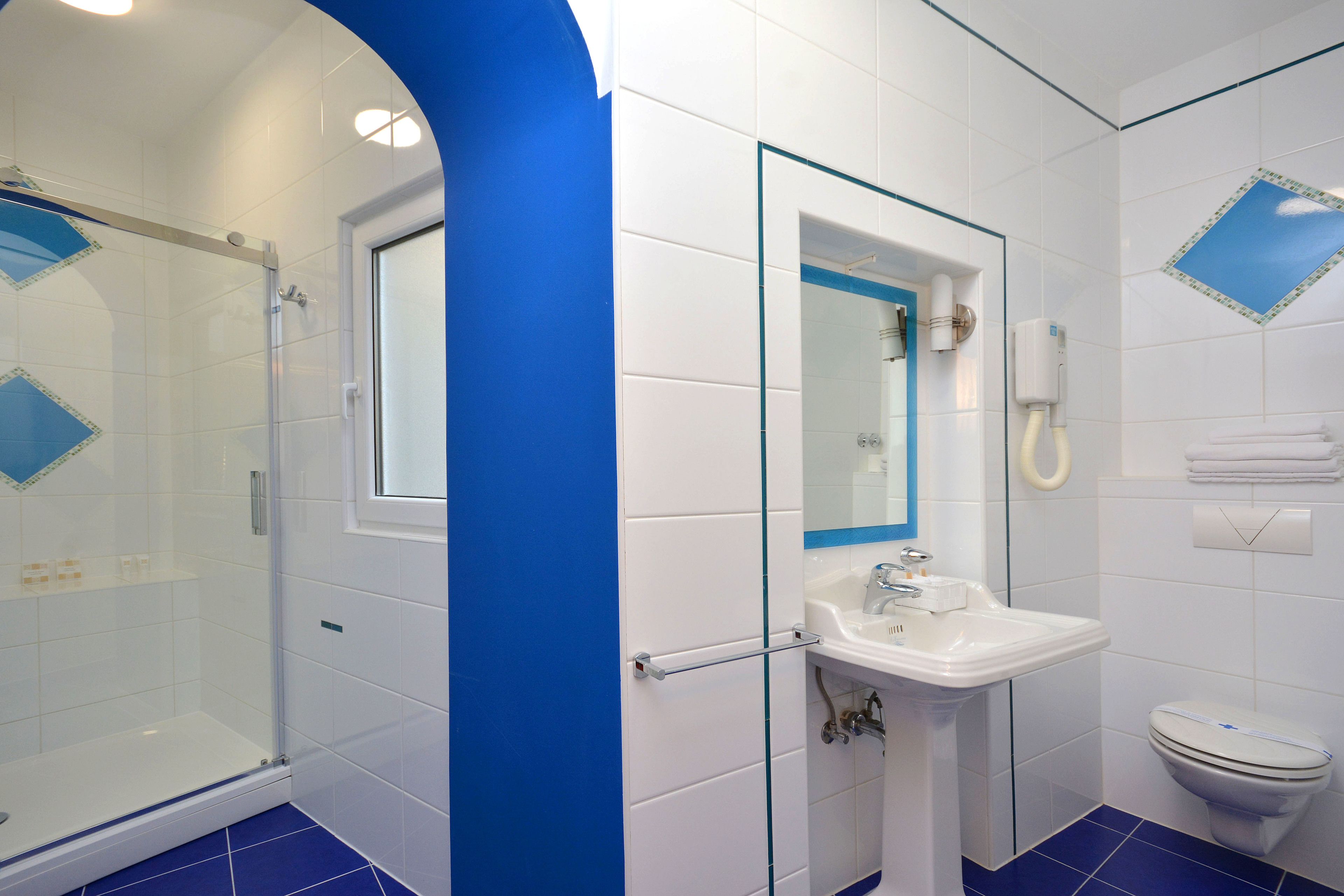 A bathroom with a glass shower enclosure, a sink, and a toilet.