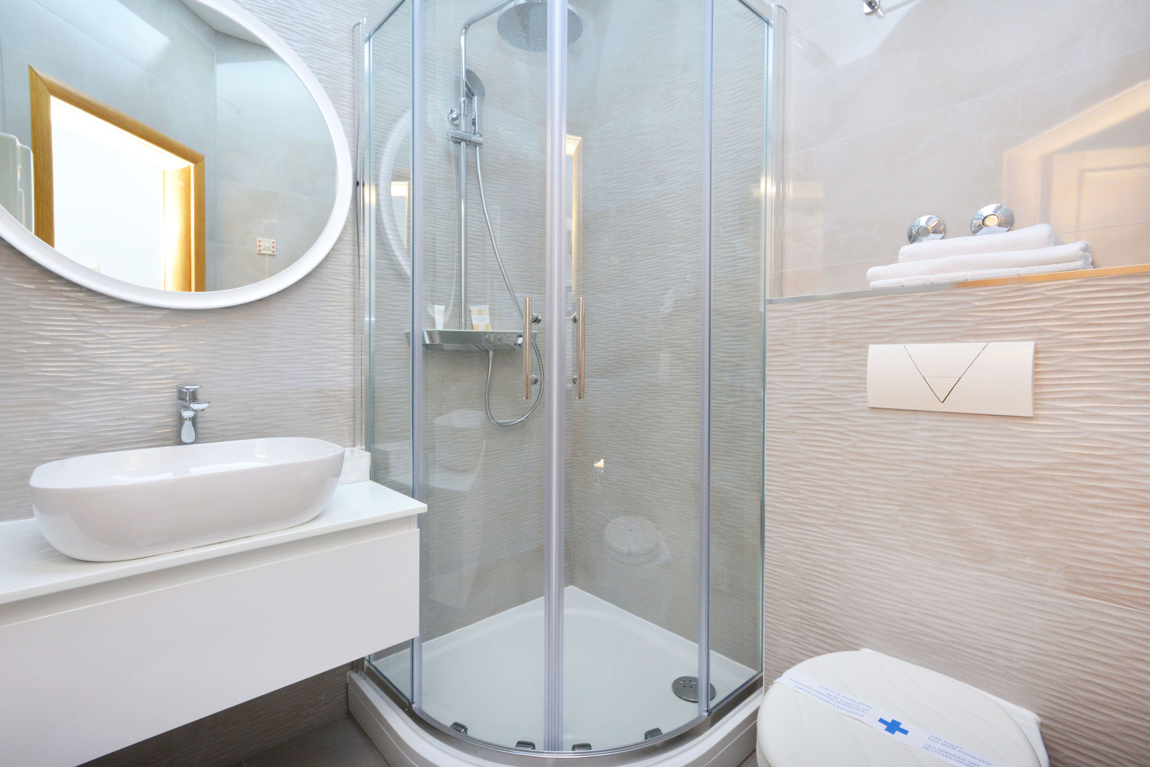 A modern bathroom with a glass-enclosed shower, a white sink, and a toilet.