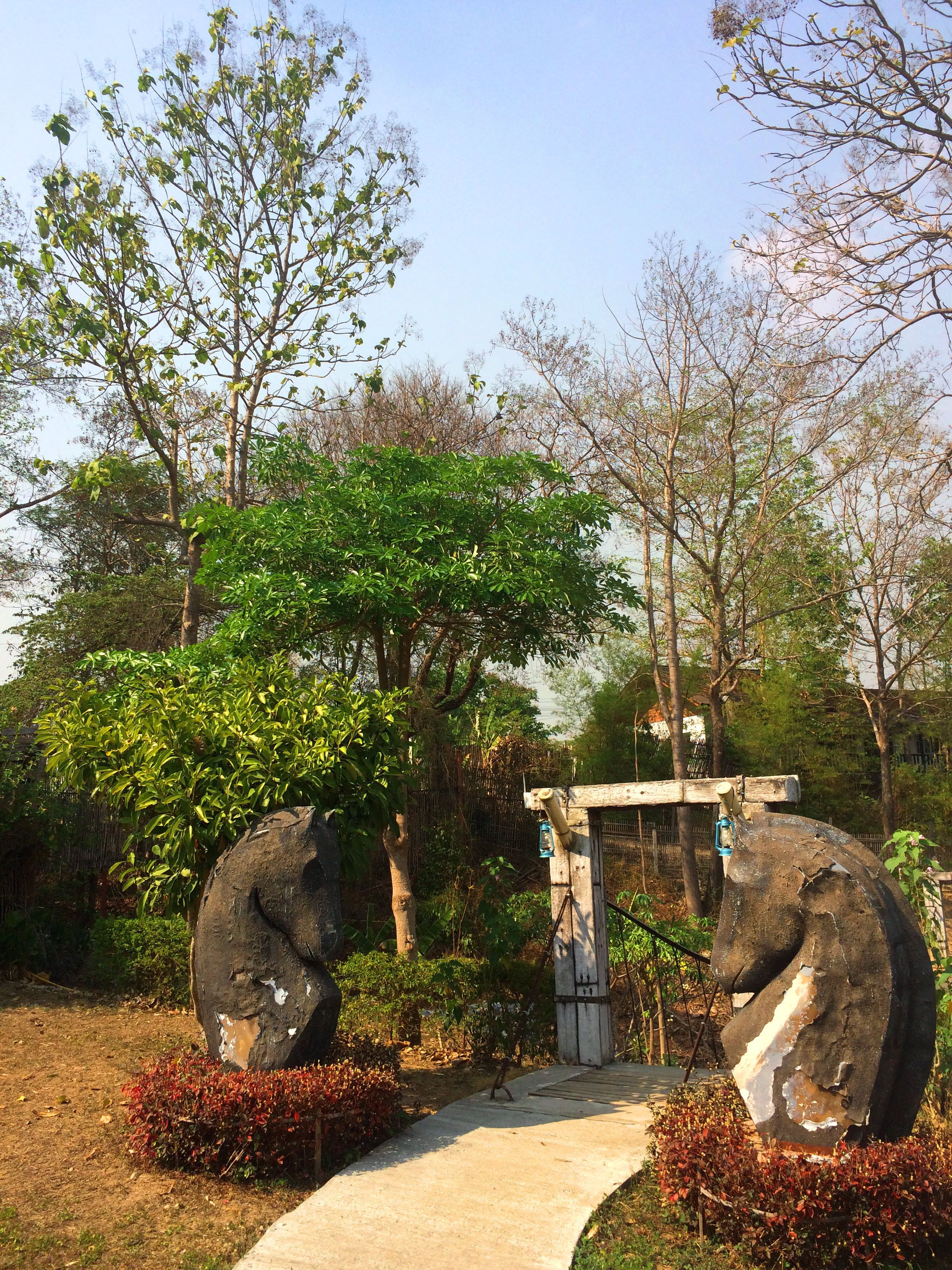 Un sentier menant à une porte traditionnelle, de part et d’autre de laquelle se trouvent des sculptures en pierre.