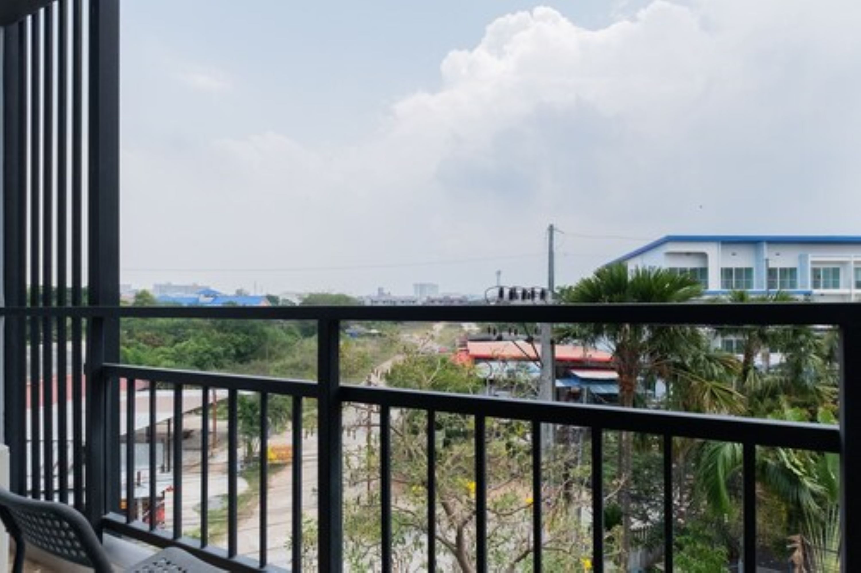 A balcony with a view of a residential area, including houses and greenery.