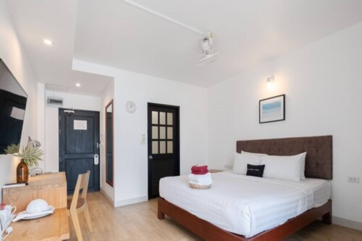 A bedroom with a bed, a wooden headboard, a wall-mounted picture, and a door with a window.