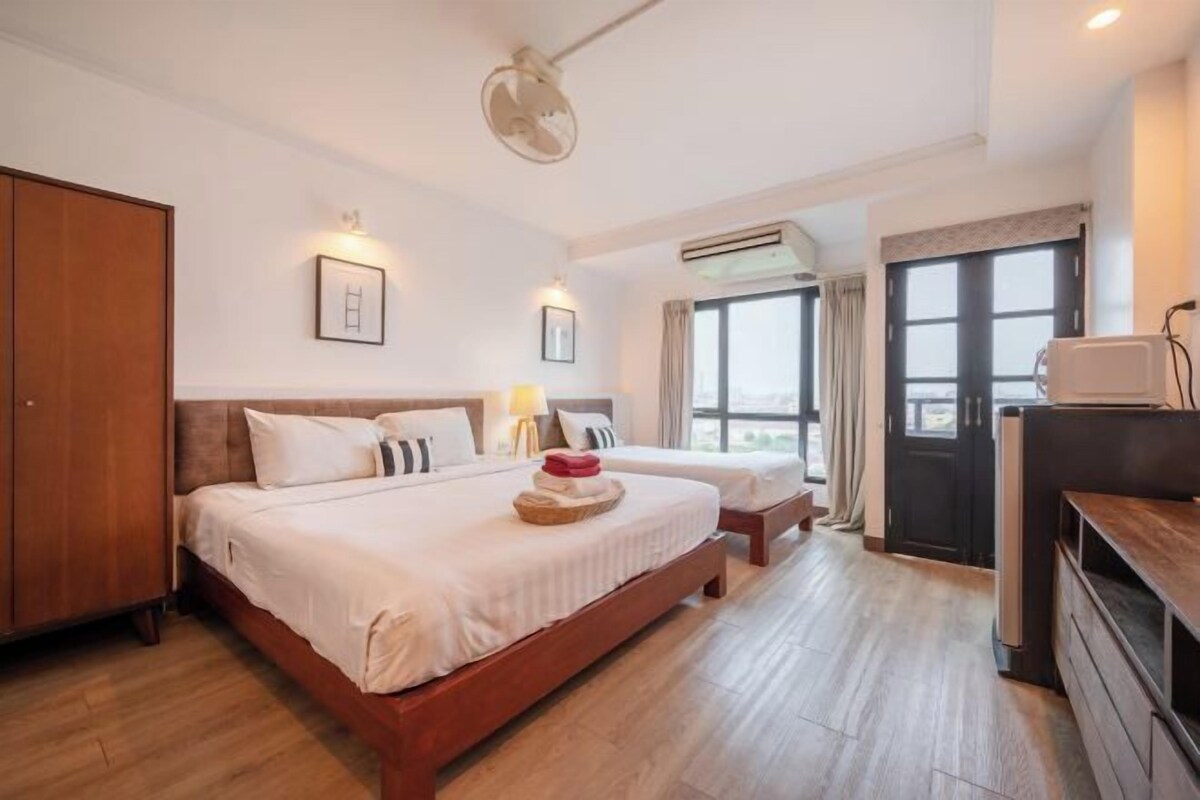 A hotel room with a large bed, a TV, an air conditioning unit, and a wardrobe.