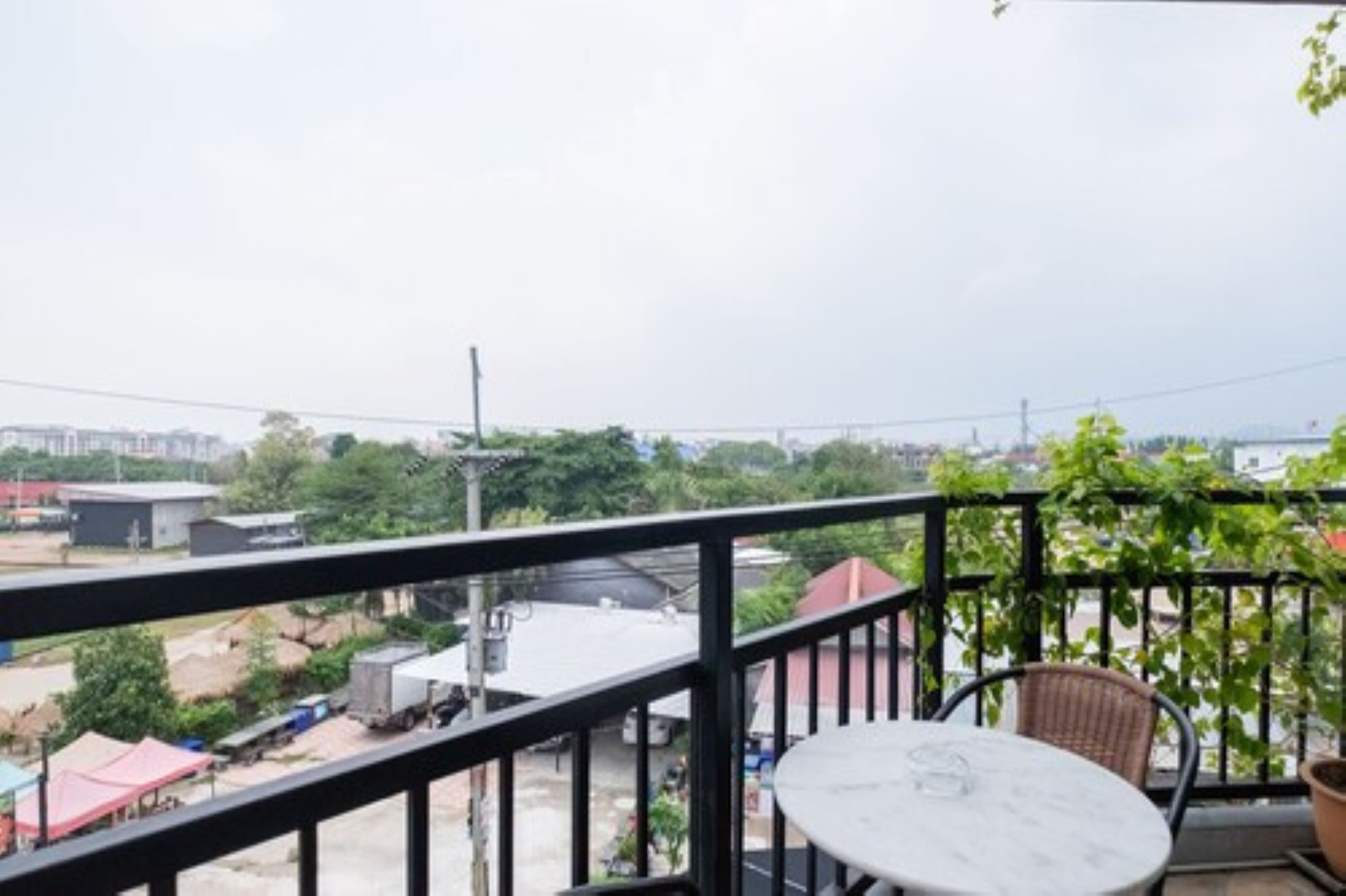 A balcony with a table and chairs, overlooking a construction site and buildings.