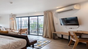 A modern hotel room with a large bed, a desk with a chair, a TV, and a balcony with curtains. - The Corner Lodge (Pattaya)