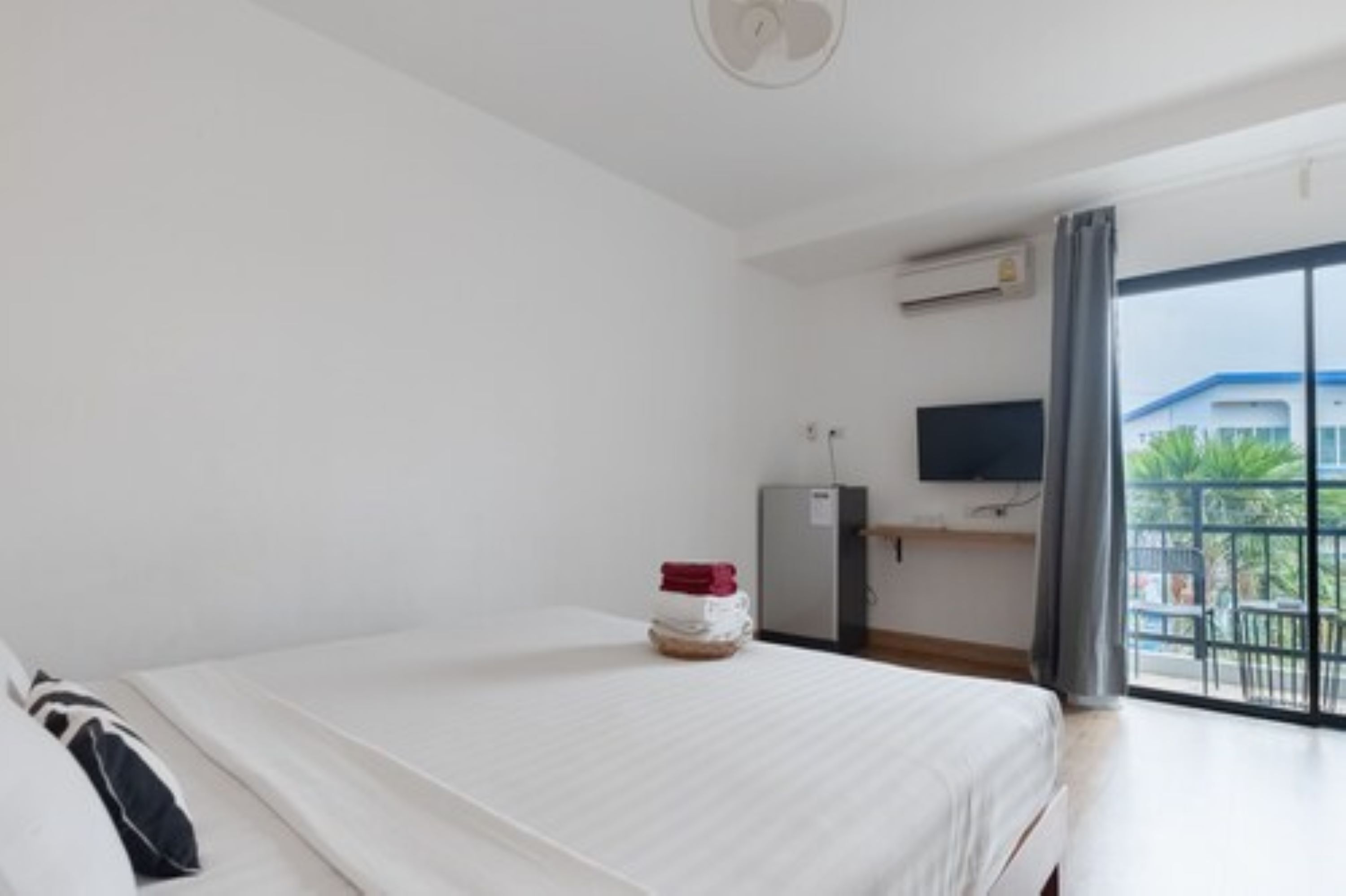 Ein Hotelzimmer mit Bett, Schreibtisch, Fernseher und einem Balkon mit Blick.
