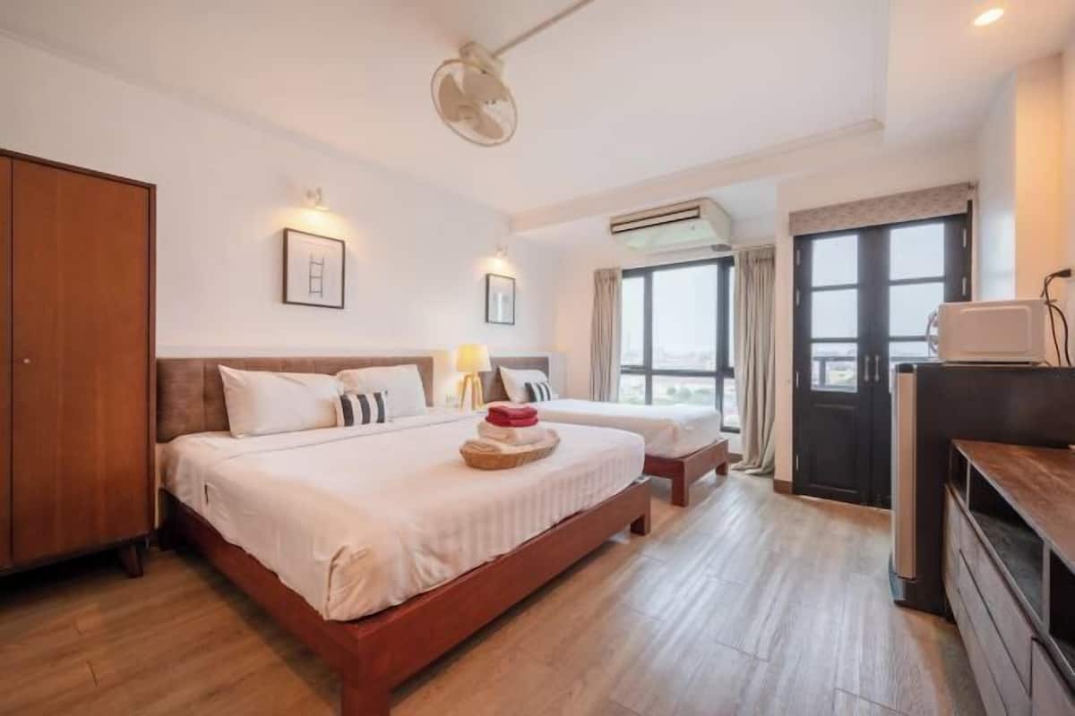 A hotel room with a large bed, a TV, an air conditioning unit, and a wardrobe.