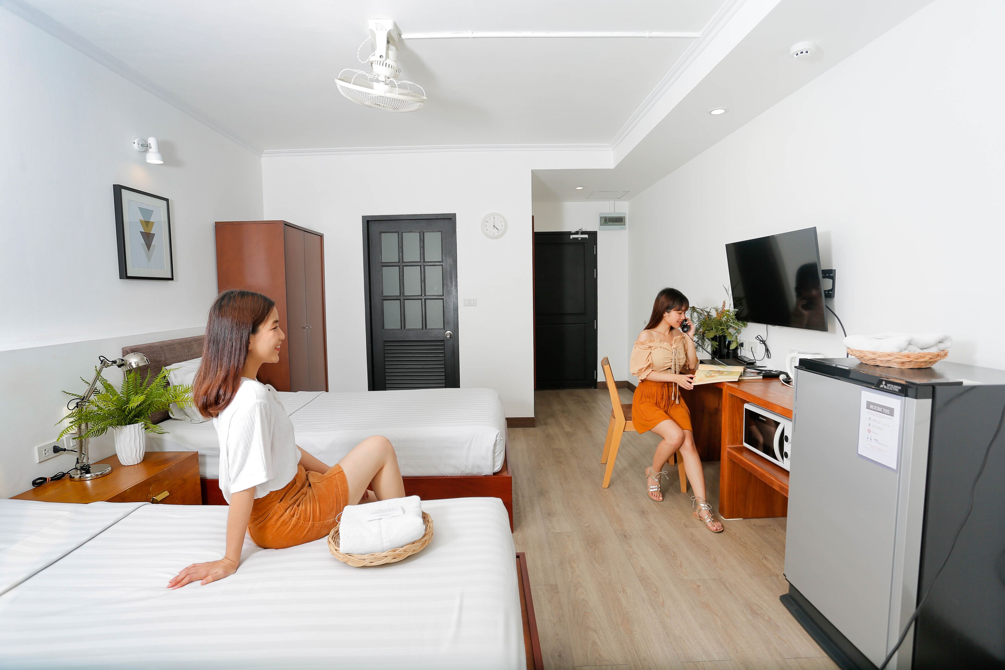 Une chambre d’hôtel avec deux lits, un bureau, une télévision et un réfrigérateur.
