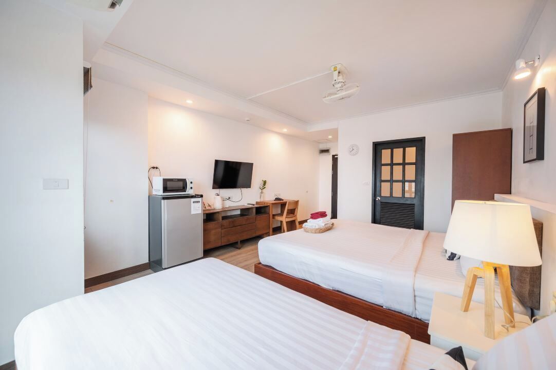 A hotel room with two beds, a desk with a computer, a television, and a window with a view of the outside.