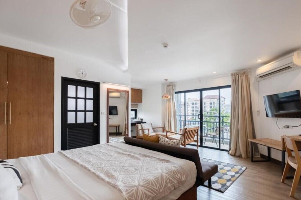 Une chambre d’hôtel équipée d’un lit, d’un bureau, d’une télévision, d’un balcon avec vue et de la climatisation.