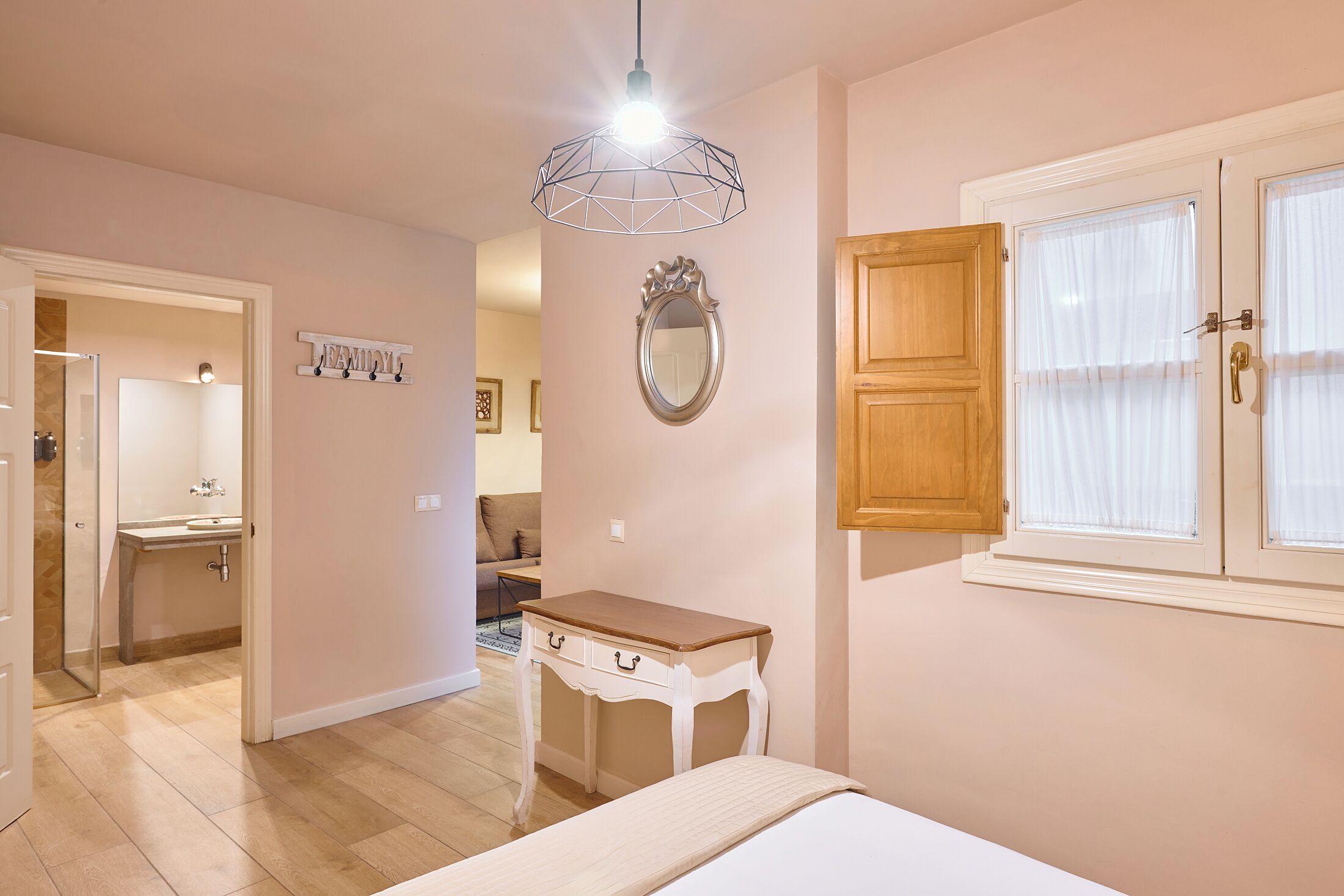 Une chambre à coucher avec un lit, une table de chevet, un miroir et une fenêtre avec des rideaux.