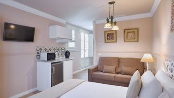 Un dormitorio con cama, sofá, televisión, microondas y lámpara.